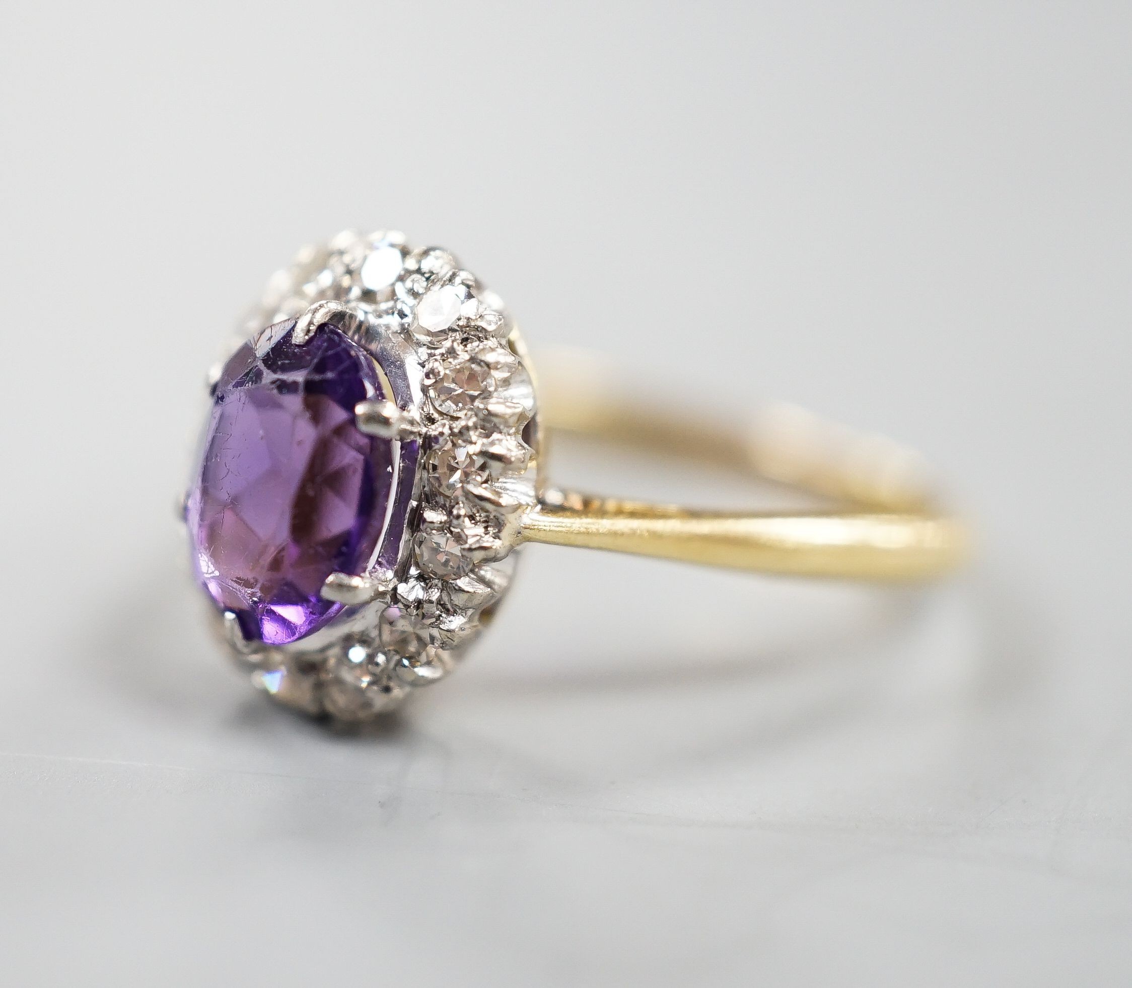 An 18ct, amethyst and diamond set oval cluster ring, size O/P, gross weight 3 grams.